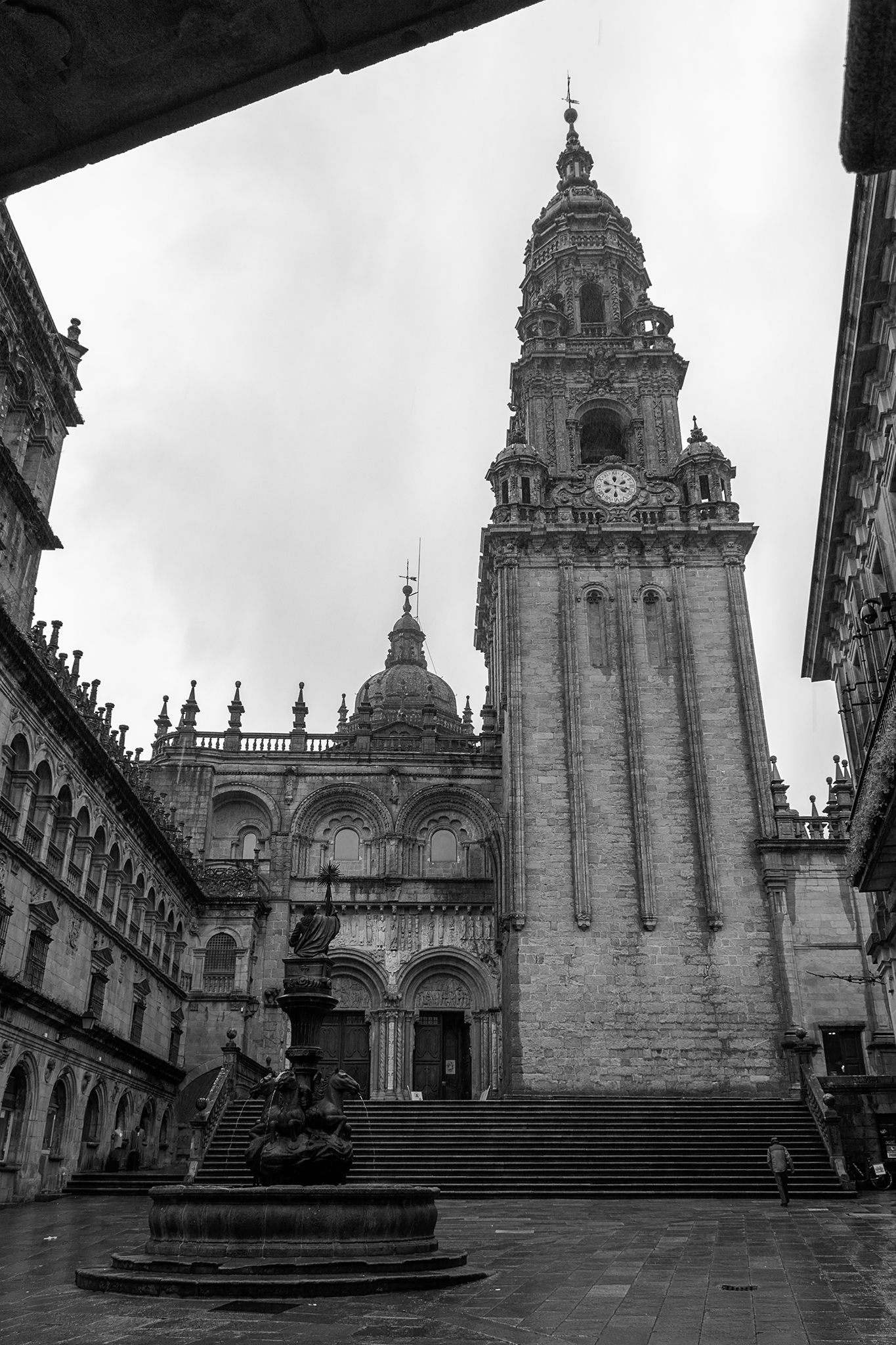 As is common in the squares and small streets that surround the Cathedral of Compostela, Platerías Square receives its name from the ancient trades and artisan activities that were developed historically.</br></br>Both the Plaza de Platerías and the north facade of the basilica are named after the workshops of goldsmiths and silversmiths that were located in this area during the Middle Ages, a custom that is maintained until the current era in which many establishments of jewelry and more specifically of artisan silversmiths are still preserved.</br></br>In the center of the square we find the Fountain of the Horses, which was originally located inside the cloister of the Cathedral, and on the right, more than 70 meters high, you can see the Clock Tower, with its lower gothic part and with later additions in baroque style on the upper part.